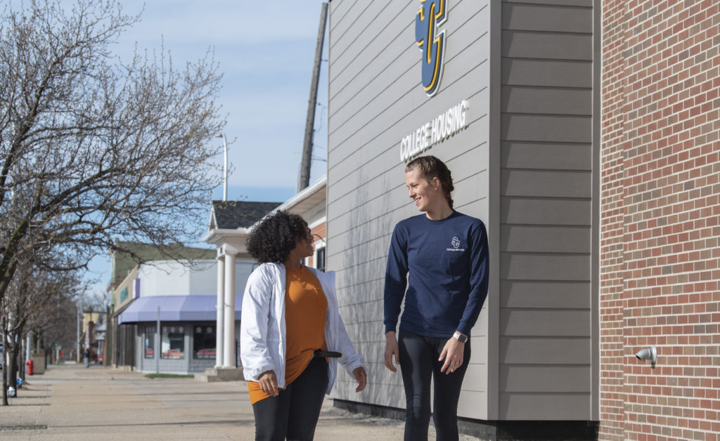 Two female students walking in front of College Housing.